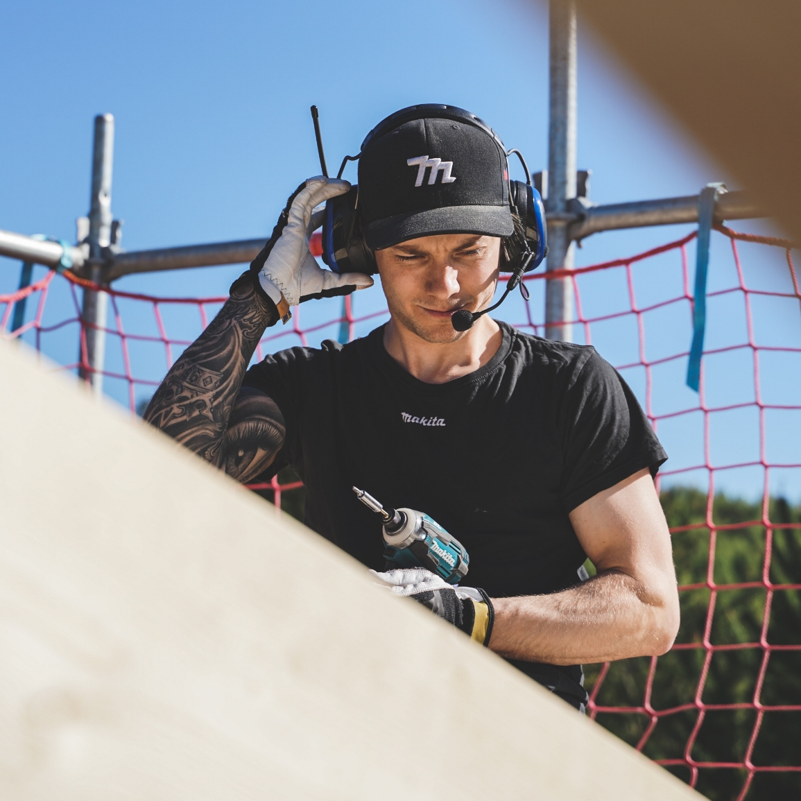 Bild på byggarbetare med hörselkåpor och skruvdragare